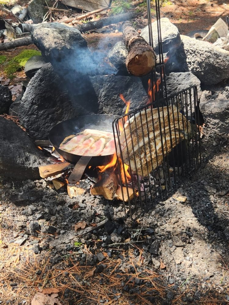 Fresh Salmon and bacon cooking over a campfire in the Maine woods.